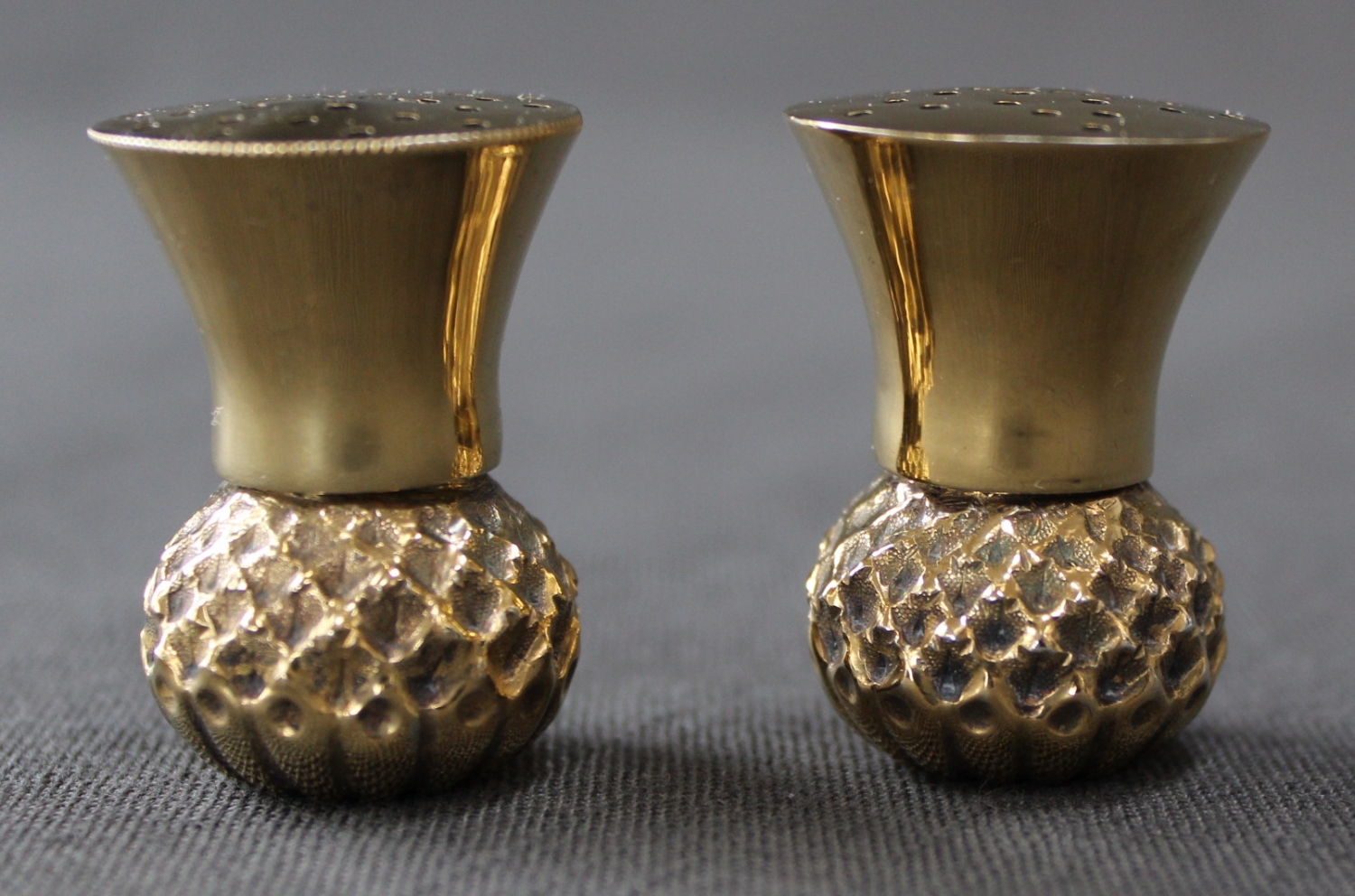A pair of silver-gilt thistle pepperettes